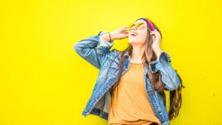 smiling woman looking upright standing against yellow wall