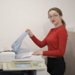 serious female office worker using printer in workplace