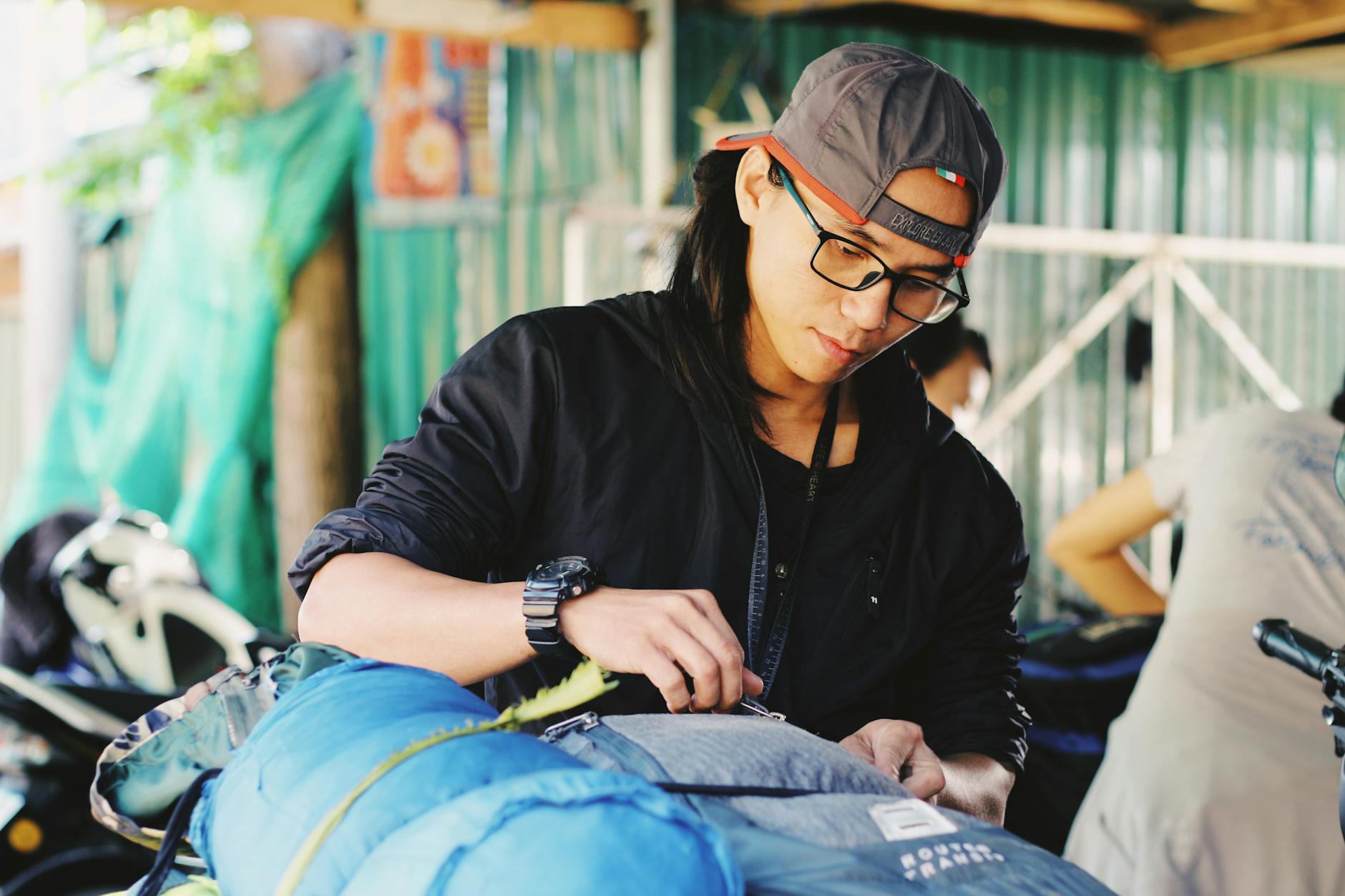 young ethnic man packing backpacks before trip