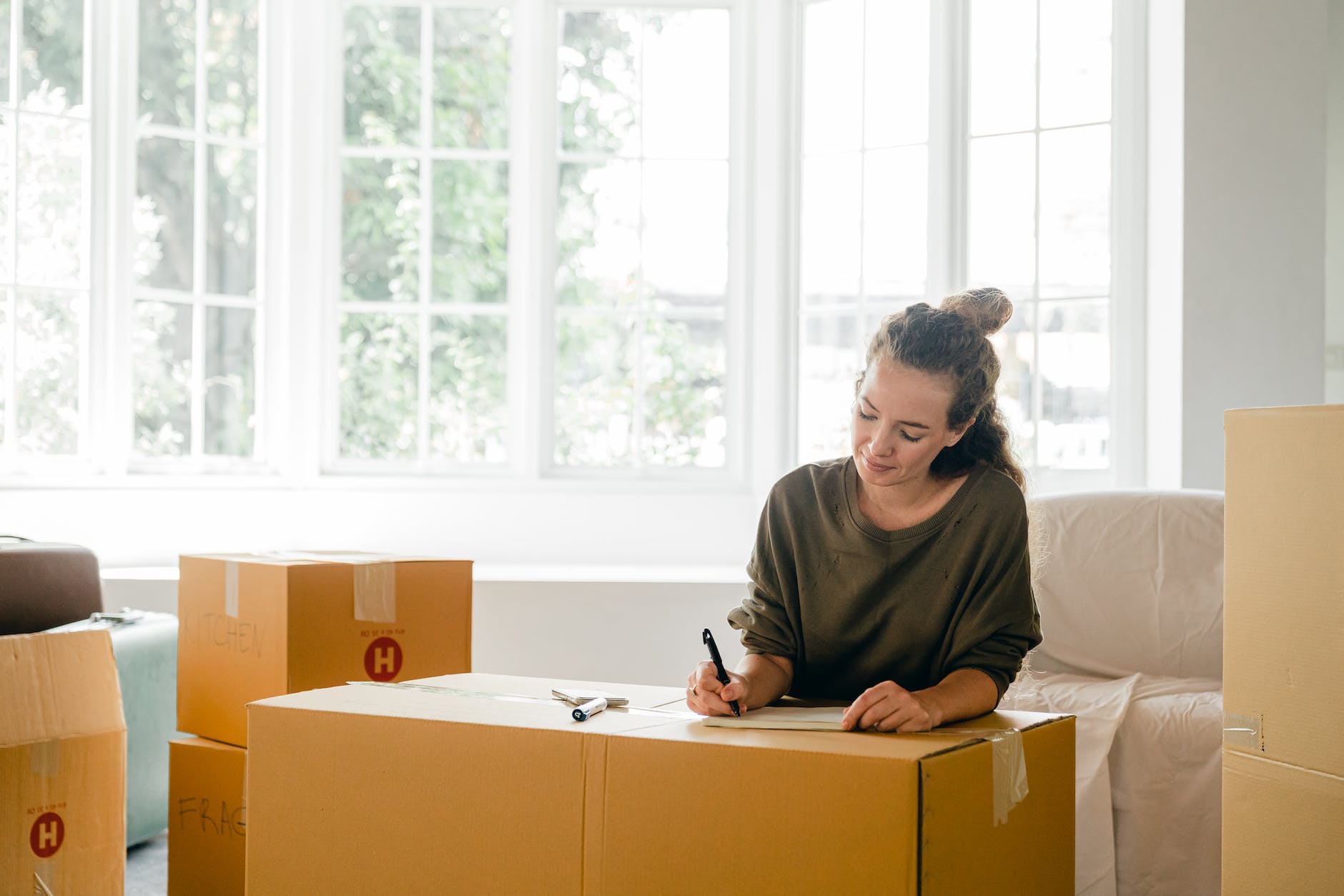 woman signing box near large window in sunlight at home