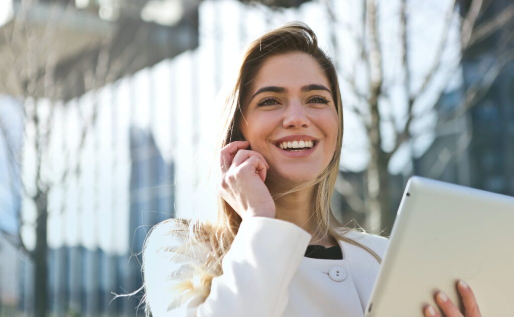 woman in white blazer holding tablet computer