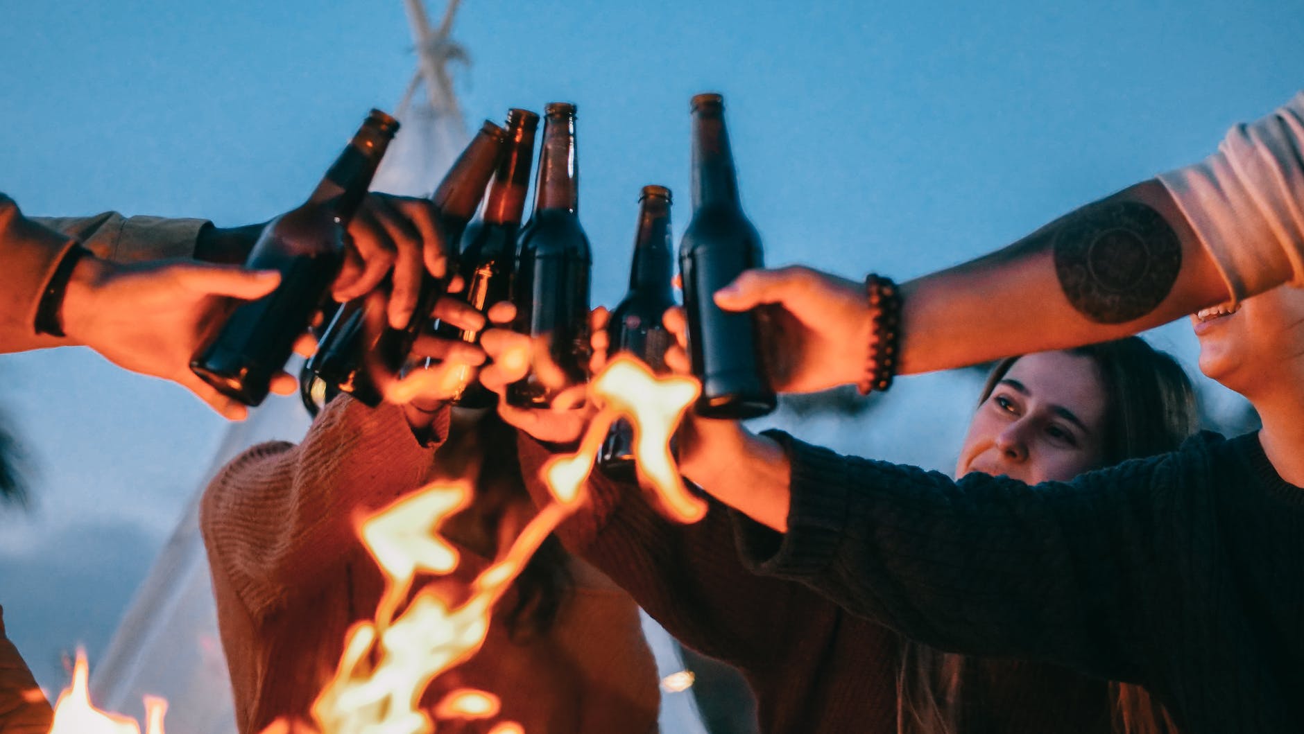 group of friends clinking beer bottles