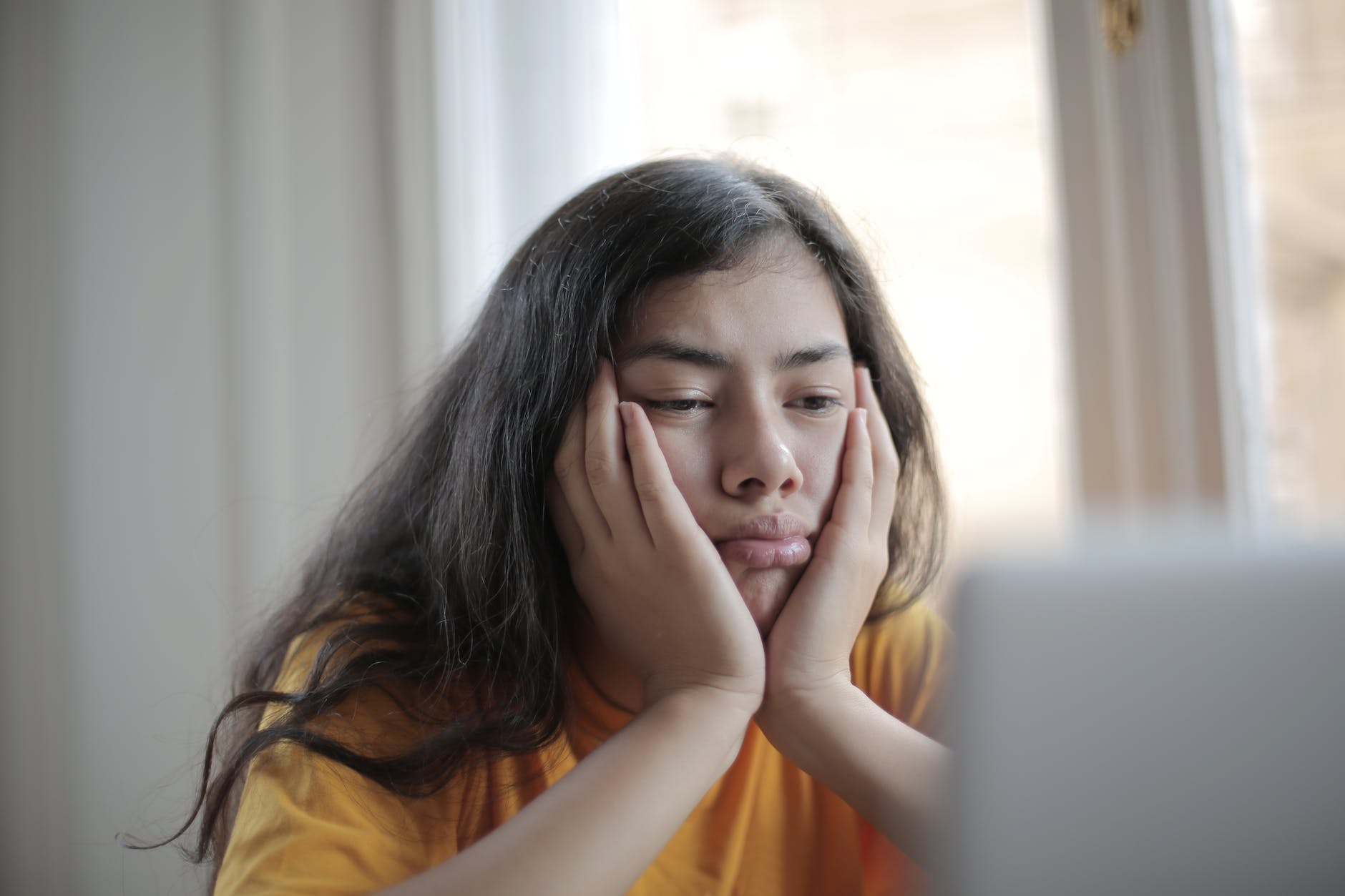 melancholic woman watching video on laptop at home