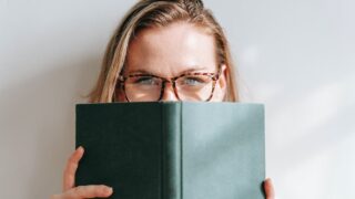 smart student in eyewear with textbook in sunshine