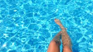 person feet dipping on pool