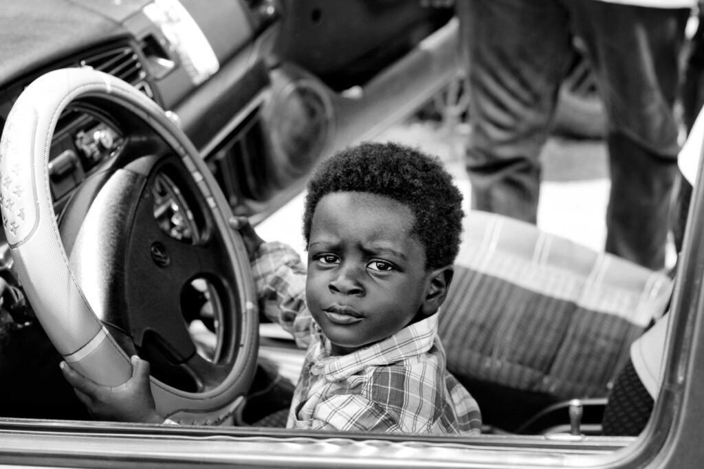 grayscale photo of boy riding car