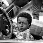 grayscale photo of boy riding car