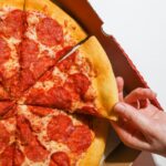person holding a slice of pizza