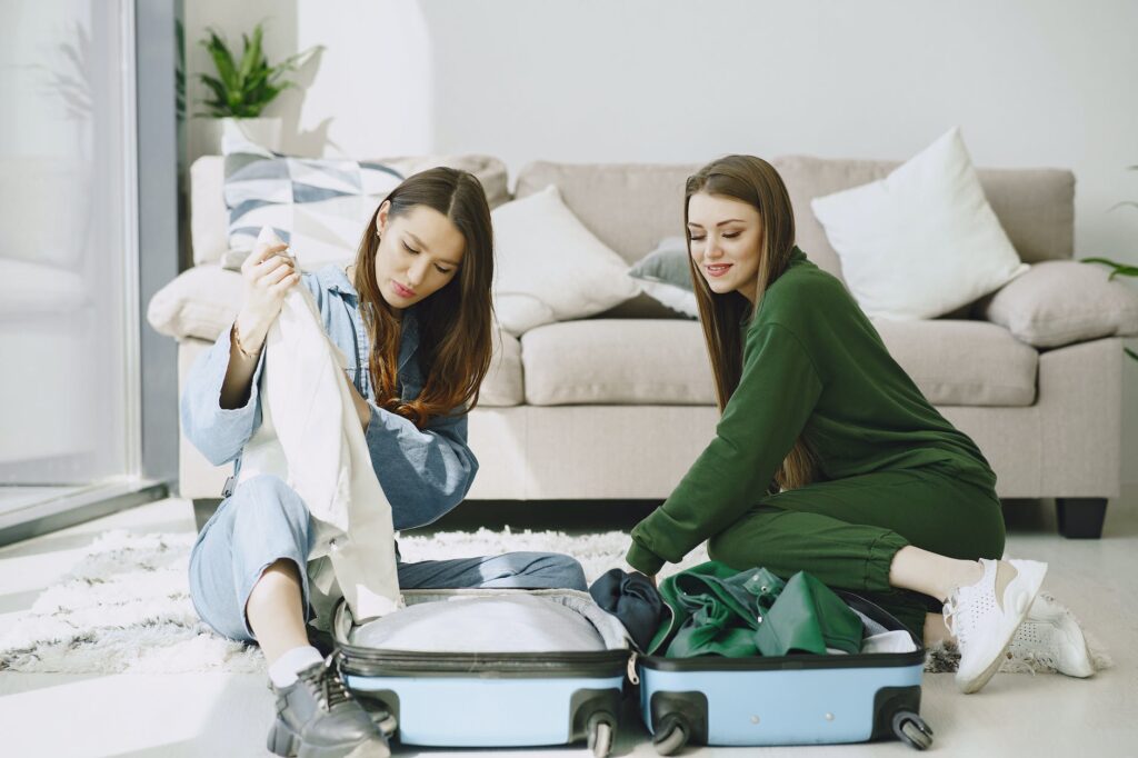 positive women unpacking luggage in hotel