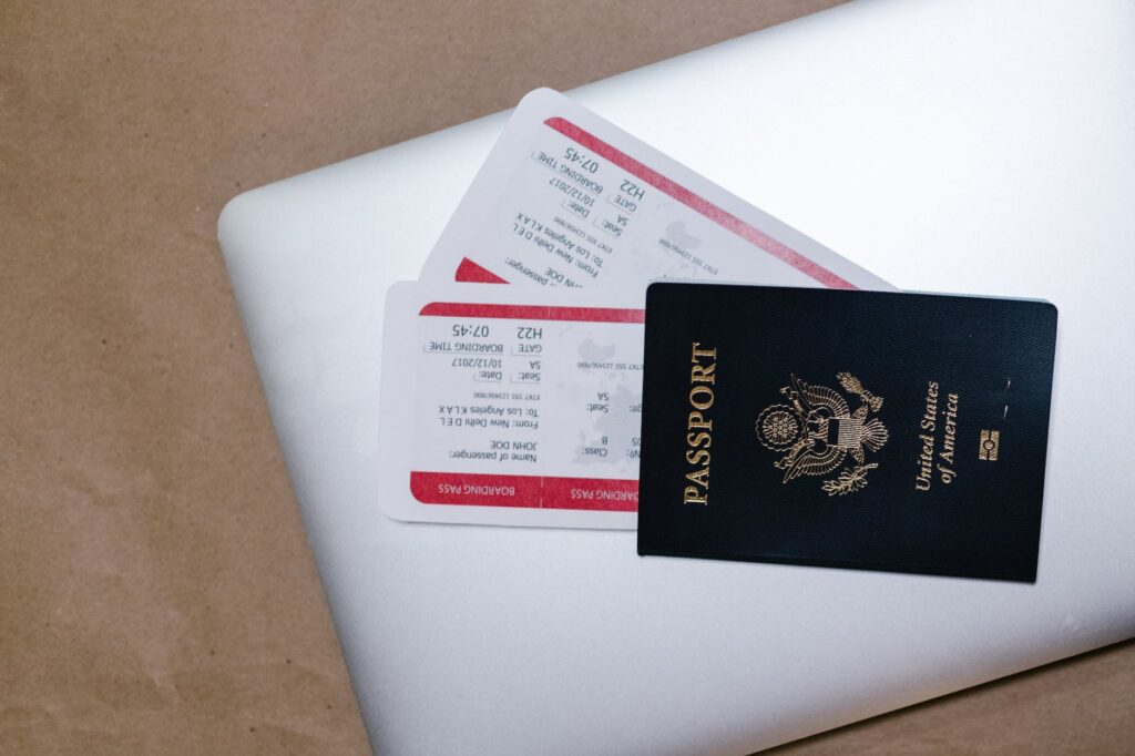 close up shot of a passport and tickets on top of a laptop