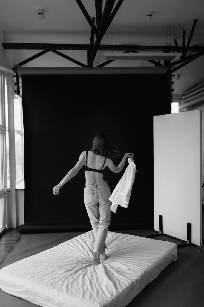 woman in bra standing on mattress in black and white