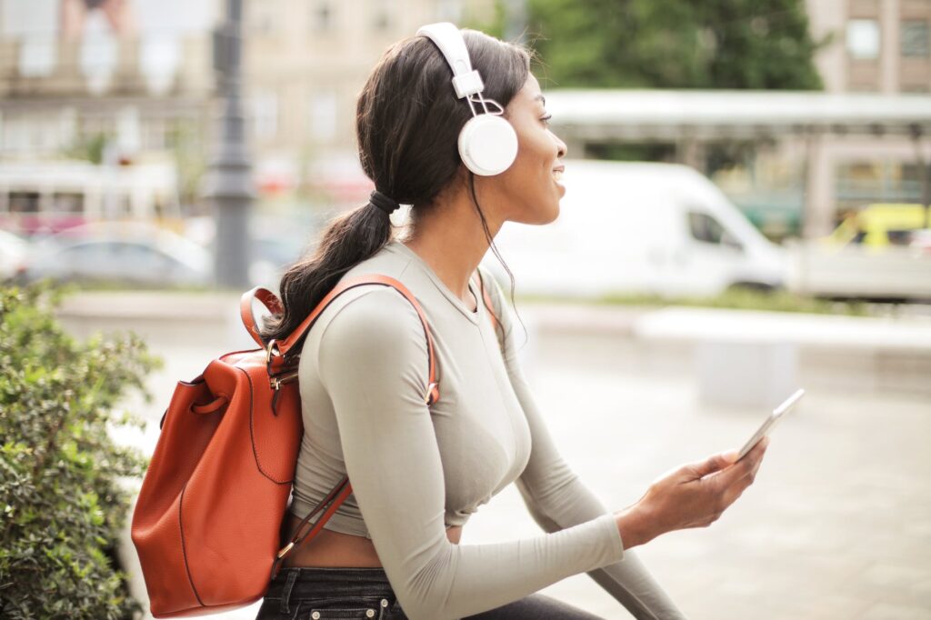shallow focus photo of woman holding smartphone while listening to music