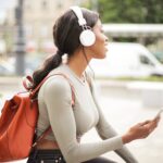shallow focus photo of woman holding smartphone while listening to music