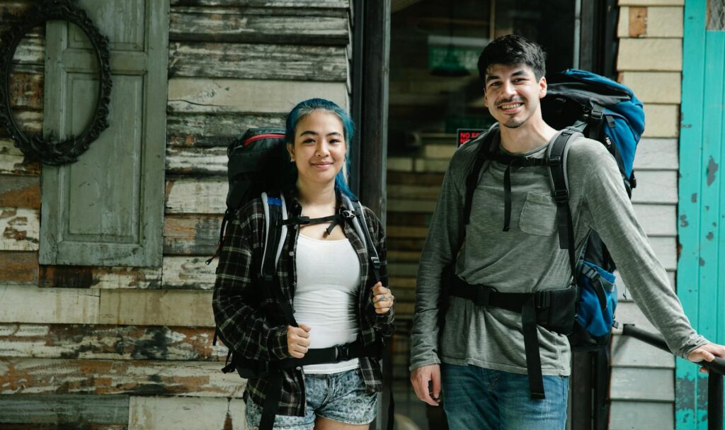 multiethnic couple of tourists standing with backpacks