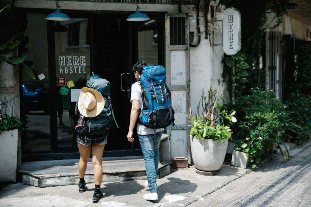 unrecognizable couple of travellers with backpacks entering hotel