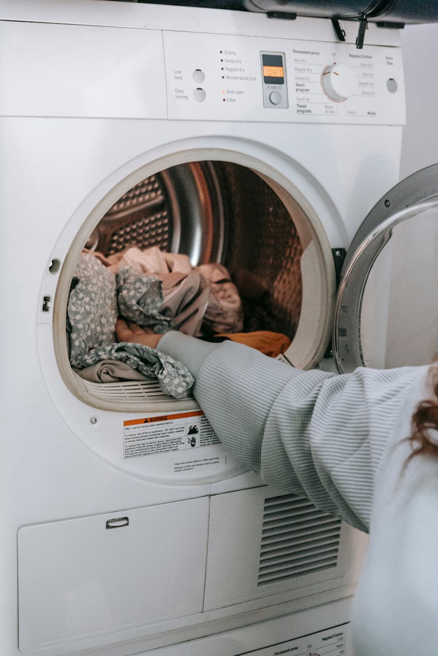 anonymous woman loading clothes in washing machine