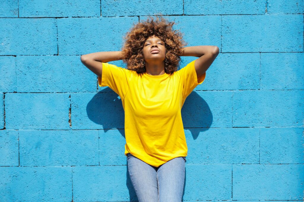 a lady in yellow shirt leaning against blue brick wall