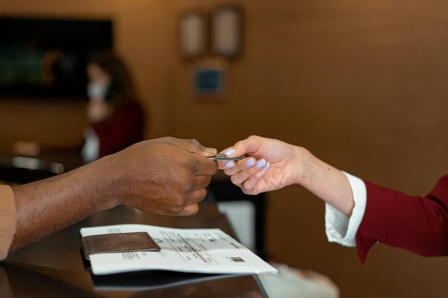 man handing a credit card to a hotel receptionist